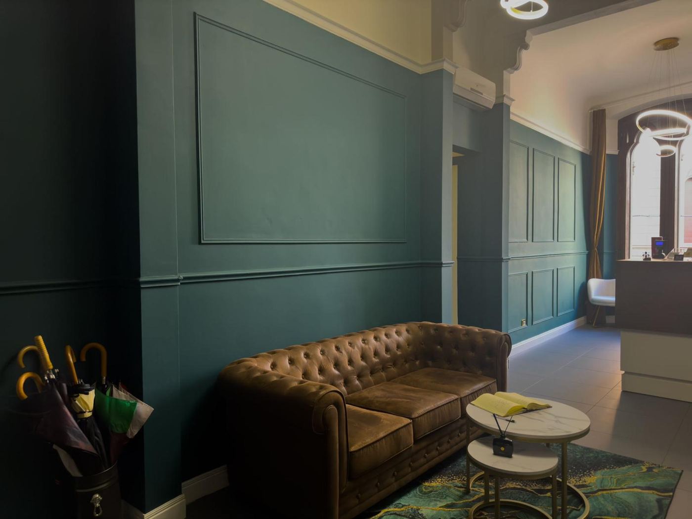 Il salotto con divano Chesterfield e boiserie verde petrolio